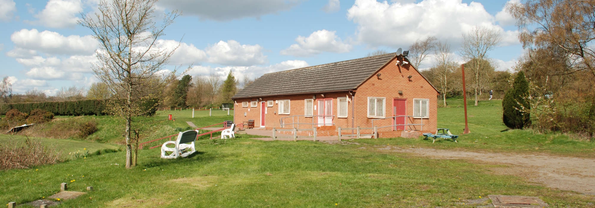Sports Pavillion can be seen in the background, two white chairs are to the left of the pavillion